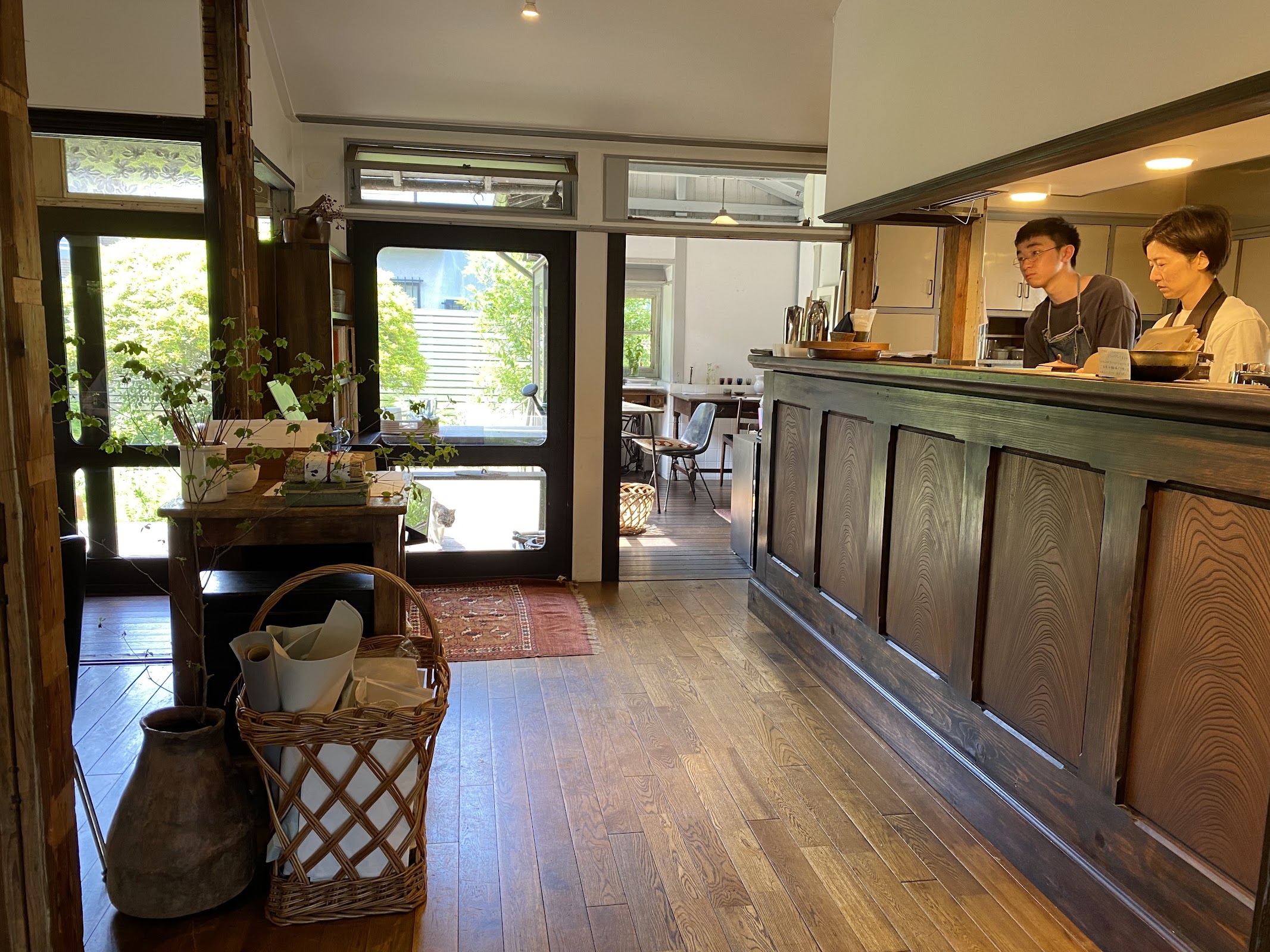 木の床と杉板のカウンター。奥でスタッフが二名、開店前の作業を行っている。